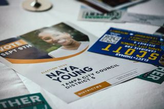 Campaign flyer for Naya Young, Tampa City Council on a table with other literature. Thomas Scott's flyer can be seen upside down to the right.