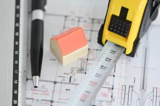 Pen and tape measure laying on a blueprint.