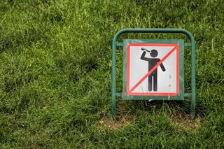 stick figure holding bottle to mouth on a sign with a red box and line through it.