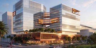 Artist rendering of two glass mid-rise towers, roughly 15 stories each, joined by bronze-clad sky bridges and set on a shared retail podium with a rooftop terrace; a street corner with cars and pedestrians in the foreground, and the curved roof of the ballpark visible at right.